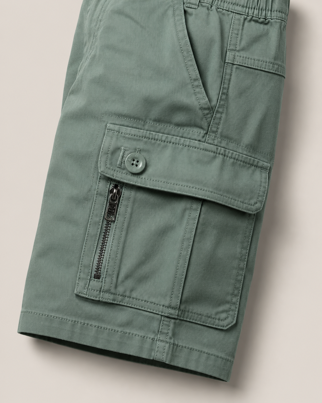 Close-up of a DF ZENS sage cargo pocket with button flap and side zip