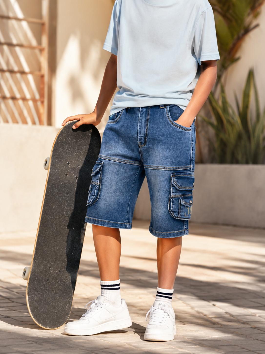 Boy in DF ZENS denim cargo shorts with a skateboard